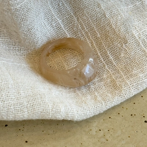 Macro detail of amber resin ring with swirl pattern on a textured ceramic surface