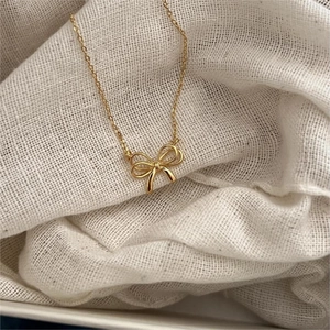 Elegant gold bow pendant necklace made of 925 sterling silver on natural linen fabric