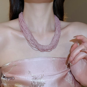 Close-up of multilayer pink beaded necklace with silk ribbon bow on female model
