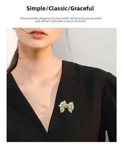 Detail of elegant gold bow brooch with pearl inlay worn on black fabric for a stylish look