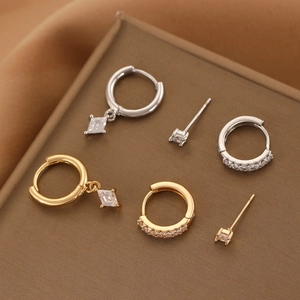 Detailed close-up of gold and silver rhumbus pendant earrings with cubic zirconia stones