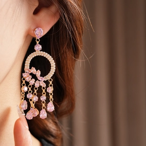 Detail of rose gold round zircon earrings featuring pink gemstone tassel on a model