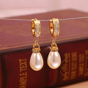 Close-up of gold hoop earrings with teardrop pearls and micro-pave diamond settings