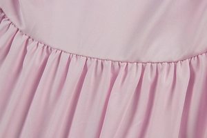 Detailed close-up of pink ruched fabric texture and fine stitching on the summer dress