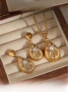 Detail of gold teardrop jewelry set with starburst engraving and pearl inlay