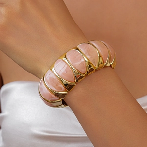 Detailed view of pink marble resin panels on a wide chunky gold stretch bracelet