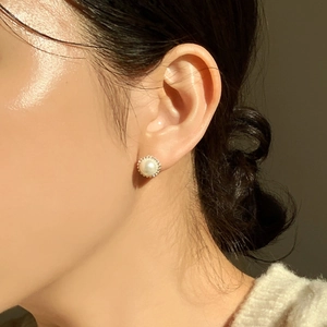 Close-up of elegant single pearl earring on model with warm natural lighting
