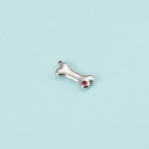 Detailed view of silver bone-shaped pendant with a sparkling red zircon stone inlay