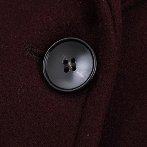 Macro shot of black button and textured burgundy wool fabric on a slim fit winter coat