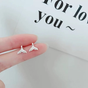 Close-up of minimalist 925 silver whale tail stud earrings with vintage embossed texture