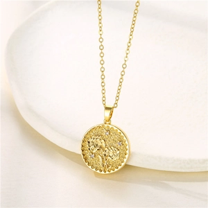 Close-up of golden sunflower embossed pendant with small crystals on a textured fabric