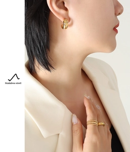 Detailed shot of 18K gold plated C-shaped earrings and star rings set in stainless steel