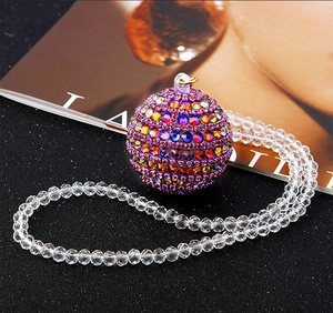 Detail of a sparkling Christmas ball pendant with colorful rhinestones on black sand