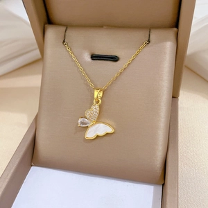 Macro detail of golden butterfly pendant with white shell and zircon inlay on soft leather