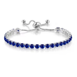 Macro detail of adjustable 4mm silver tennis bracelet featuring blue zircon claw settings