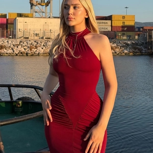 Detail of slim-fit dark red halter dress with elegant side ruching in sunset outdoor lighting