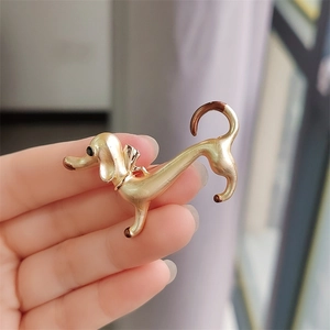 Detailed close-up of a golden dachshund enamel brooch with elegant brown accents
