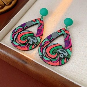Gros plan de boucles d'oreilles gouttes géométriques colorées sur plateau en bois