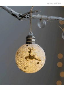 Macro view of glowing Christmas bulb ornament with golden reindeer and snowy texture