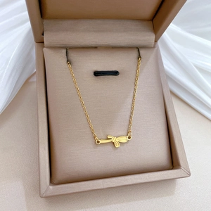 Detail of a gold bow pendant necklace resting in a premium brown jewelry gift box