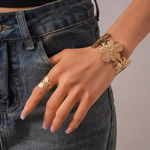Detailed close-up of golden floral metal bangle and ring with intricate petal texture