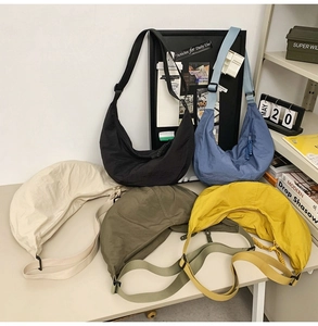 Détail de cinq sacs croissants en nylon colorés avec bandoulières réglables sur un bureau