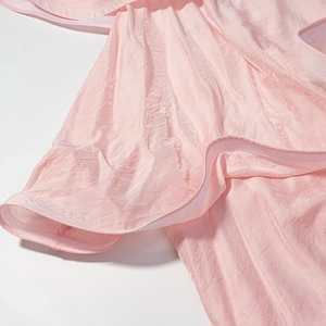 Détail du tissu satin rose montrant des plis élégants et une texture de soie lisse