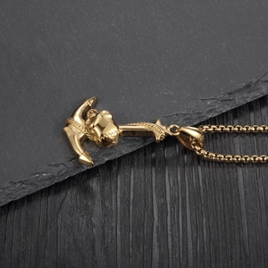 Makroaufnahme eines goldenen Piraten-Ankeranhängers mit Totenkopf auf dunklem Schiefer