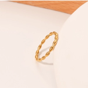 Close-up of a minimalist gold-tone titanium steel ring with textured dot pattern
