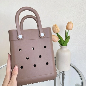 Detail of a brown EVA tote bag with hole design placed on a glass table with flowers