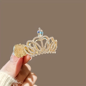 Détail d'une pince à cheveux couronne dorée avec strass et pierre précieuse en goutte