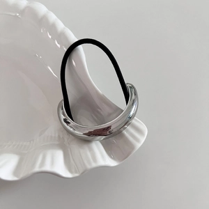Minimalist silver curved metal hair tie with high elastic black rope on shell tray