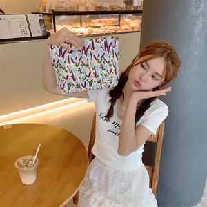 Lifestyle shot of tulip canvas makeup bag held by hand in a cozy cafe setting
