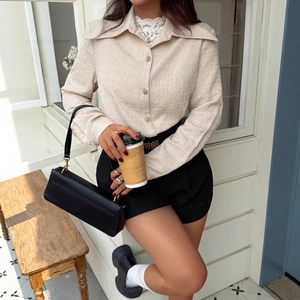 Detail of apricot textured long sleeve shirt with metal buttons and lace layering details