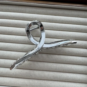 Close-up of a silver metallic hair claw clip with a strong spring on a soft velvet base