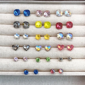 Multiple shapes of colorful crystal stud earrings in a beige velvet jewelry box