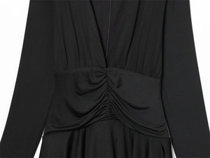 Detailed view of women's black V-neck dress featuring elegant pleated waist and soft knit fabric