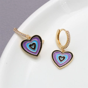 Macro detail of gold heart earrings with multi-layer purple and blue enamel and zircons