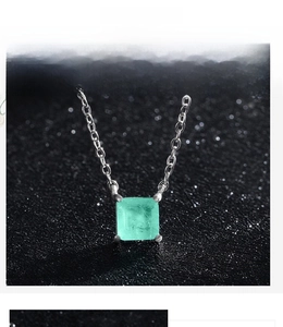 Macro shot of square green paraiba tourmaline pendant in classic four-prong silver setting