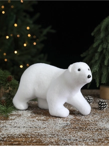 Macro shot of a white flocked polar bear figurine in a cozy winter Christmas forest setting