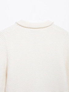 Gros plan du dos d'un pull en maille blanc avec des perles élégantes sur l'encolure
