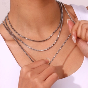 Close-up of triple-layered silver stainless steel box chain necklace worn by a model