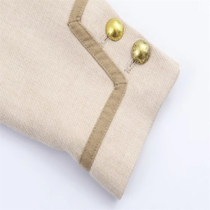 Détail du poignet en tweed beige avec des boutons dorés vintage et une bordure de couleur kaki