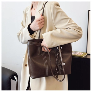 Close-up of brown tote bag featuring white contrast stitching and cute cat charm detail