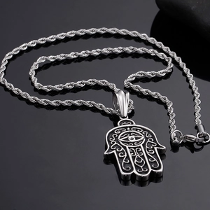 Detail of silver Hamsa hand pendant with intricate relief textures and evil eye motif