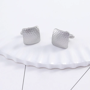 Detailed view of matte silver square cufflinks with a hammered metal texture on a tray