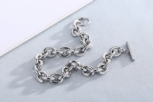 Detailed view of silver stainless steel OT buckle chain bracelet on a textured surface