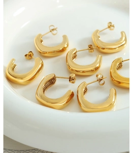 Vue rapprochée de boucles d'oreilles créoles dorées en C avec finition miroir polie