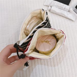 Close-up of small woven tweed cosmetic pouches showing zipper detail and interior lining