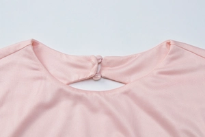 Close-up of pink knit dress collar with teardrop cutout and elegant double-button closure